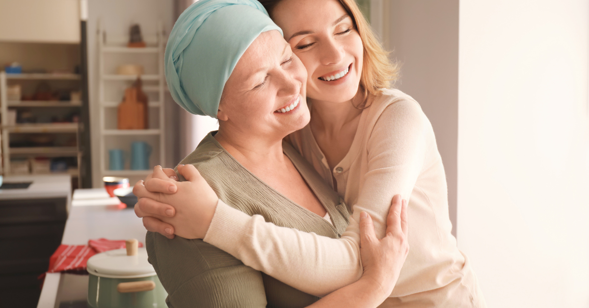 Cómo Prevenir y Detener el Cáncer de Forma Natural: Integrando Ciencia y Metabolismo 1 Mujer abrazando a su madre en la cocina, mostrando un momento de amor y apoyo emocional, mientras la madre lleva un pañuelo en la cabeza.